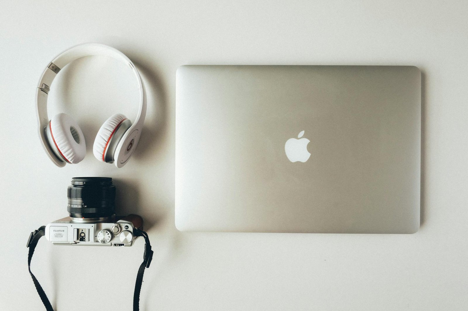 A modern flat lay of a laptop, headphones, and a camera showcasing tech essentials.